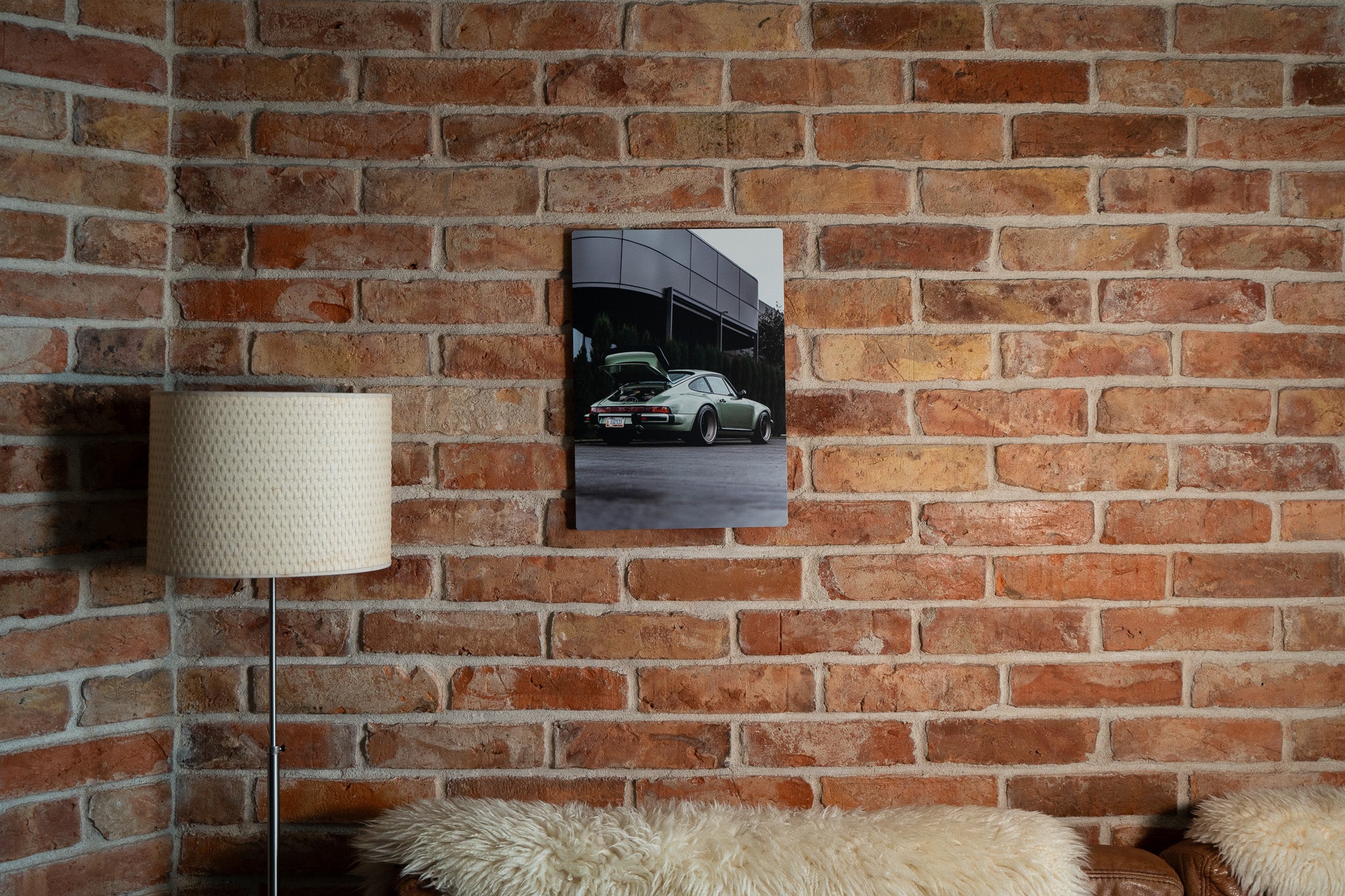 Large matte metal wall print of classic sports car against brick backdrop, timeless style.