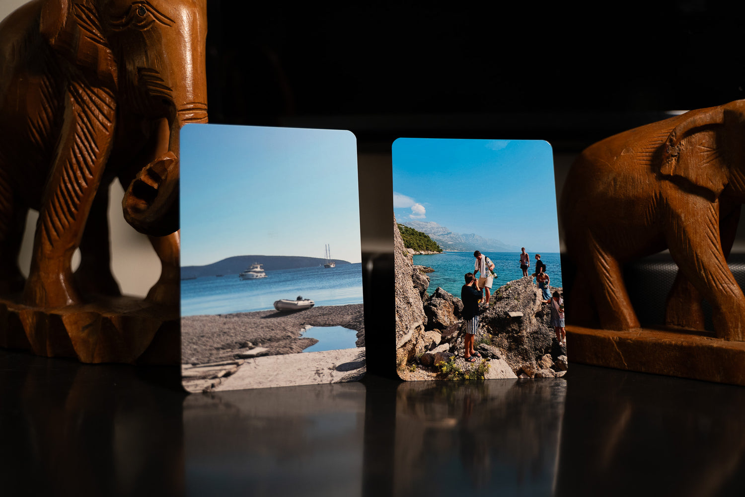 Two small glossy metal prints of beach cove and cliff hikers on stands, capturing high-resolution holiday memories.