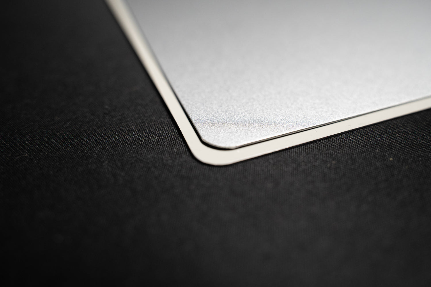 Corner close-up of large matte metal print on black background, highlighting smooth rounded corner and sleek finish.