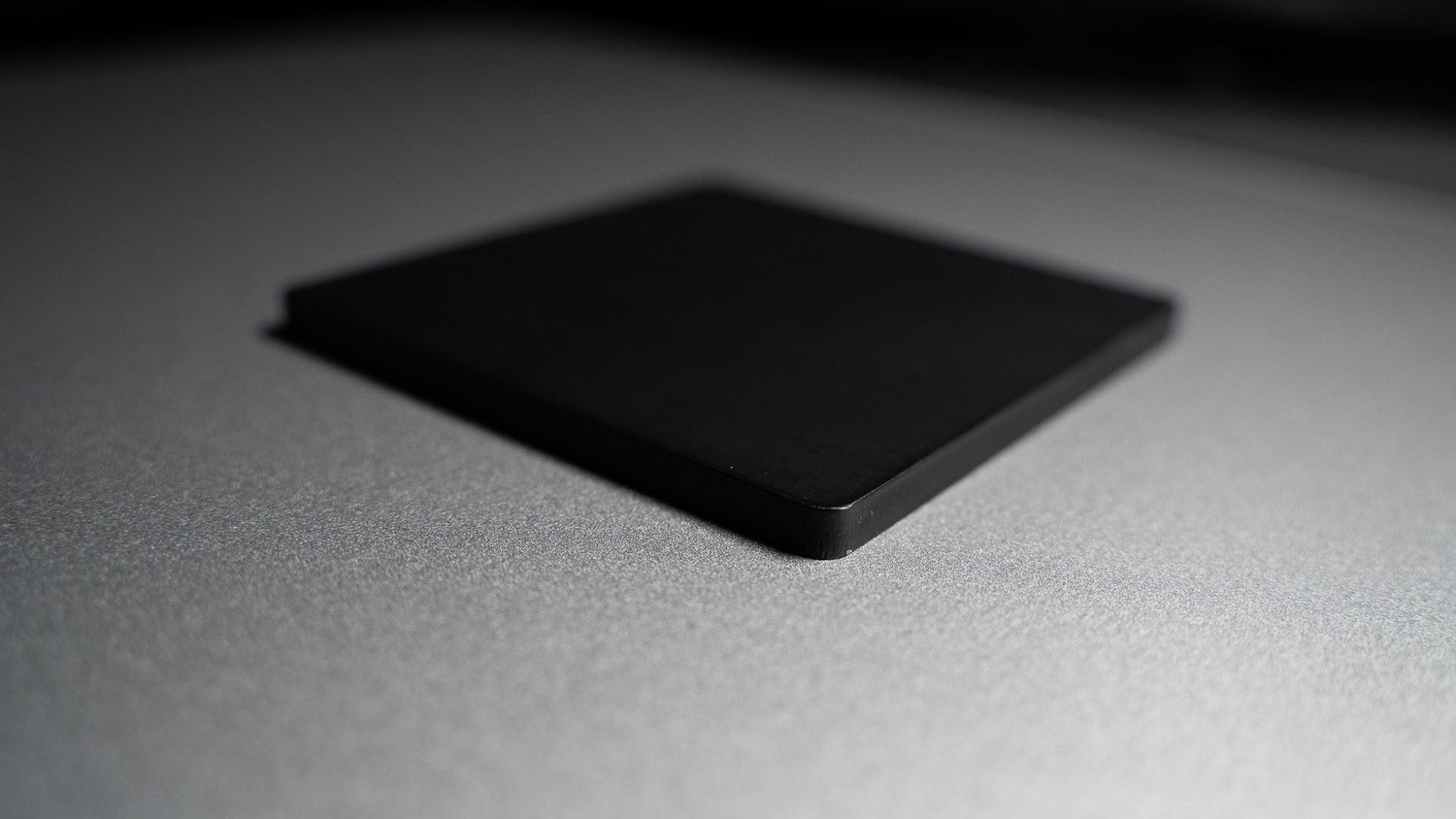 Angled view of large matte metal print face-down on black surface, showing slim profile for easy magnetic mounting