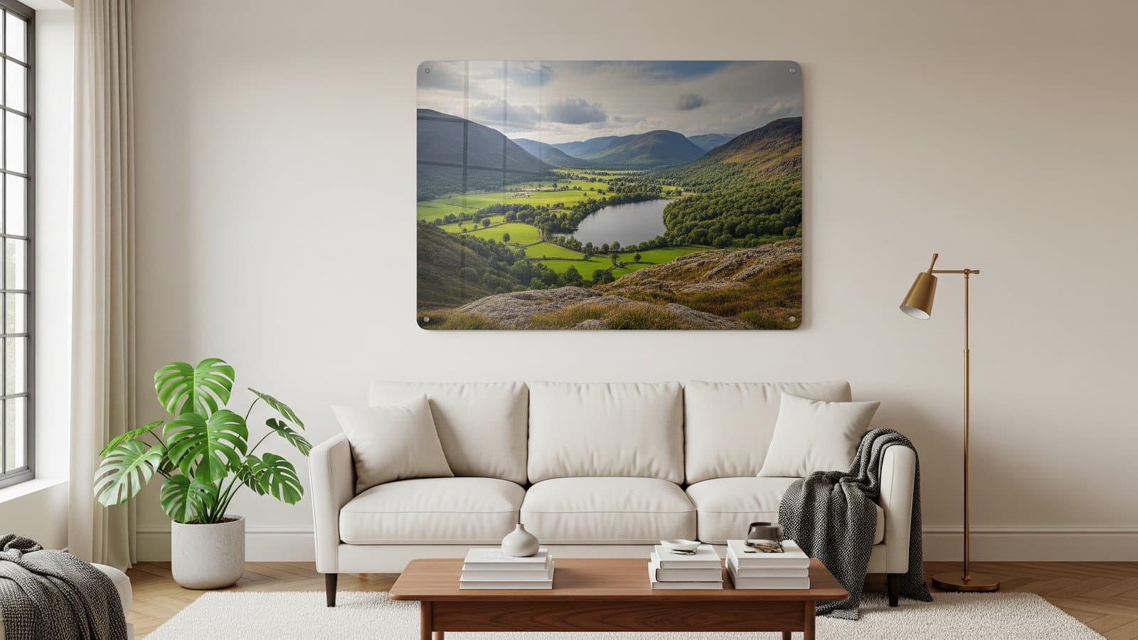 Grote glanzende metaaldruk van een Lake District landschap boven een crèmekleurige bank in een moderne woonkamer