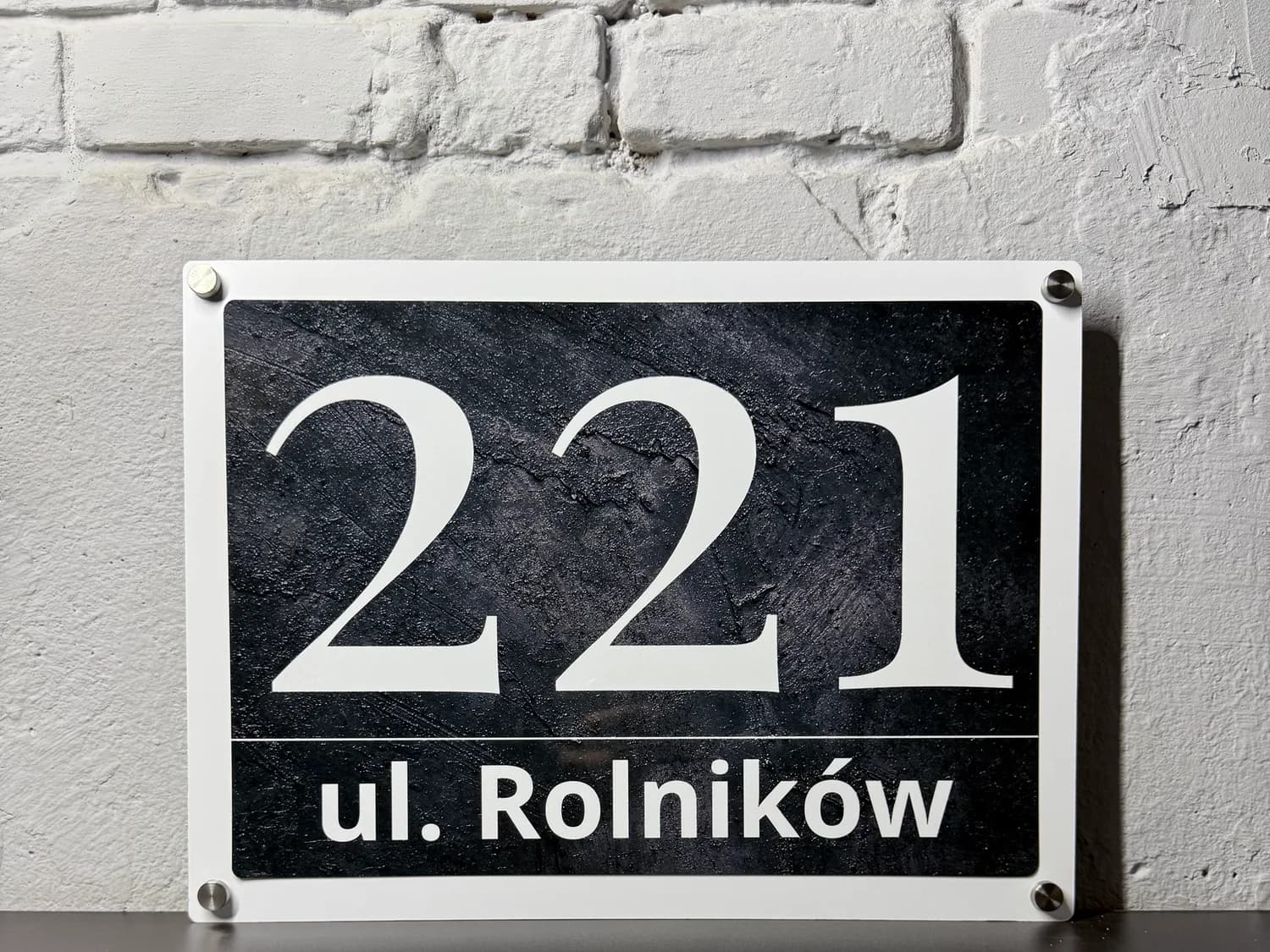 Glossy metal address sign mounted on a modern house wall