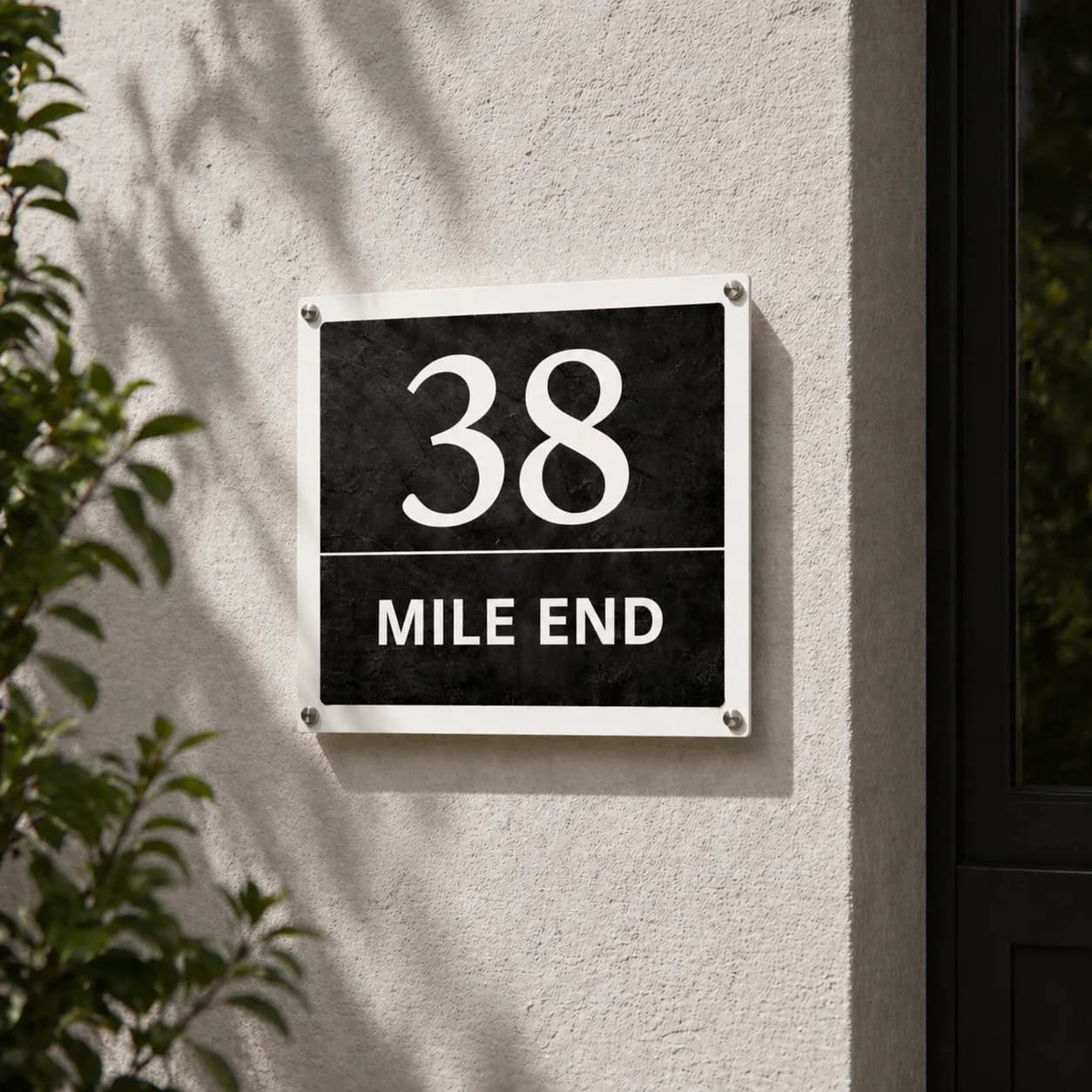 Square anthracite metal address sign, 38 Mile End, inox standoff bolts beside a front door in daylight