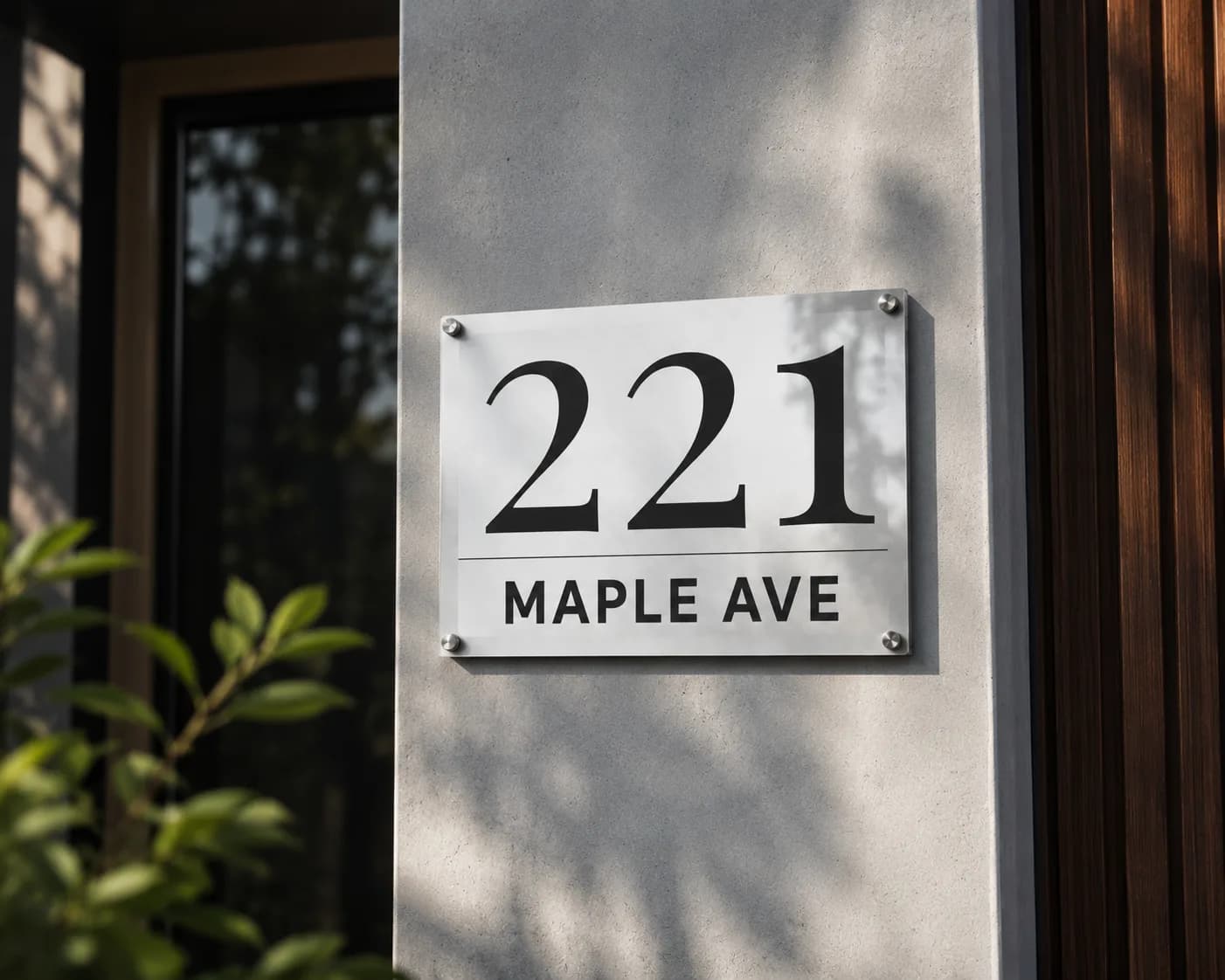 Glossy metal address sign with light marble-effect design, house number 221, on inox standoffs on a concrete pillar in warm daylight