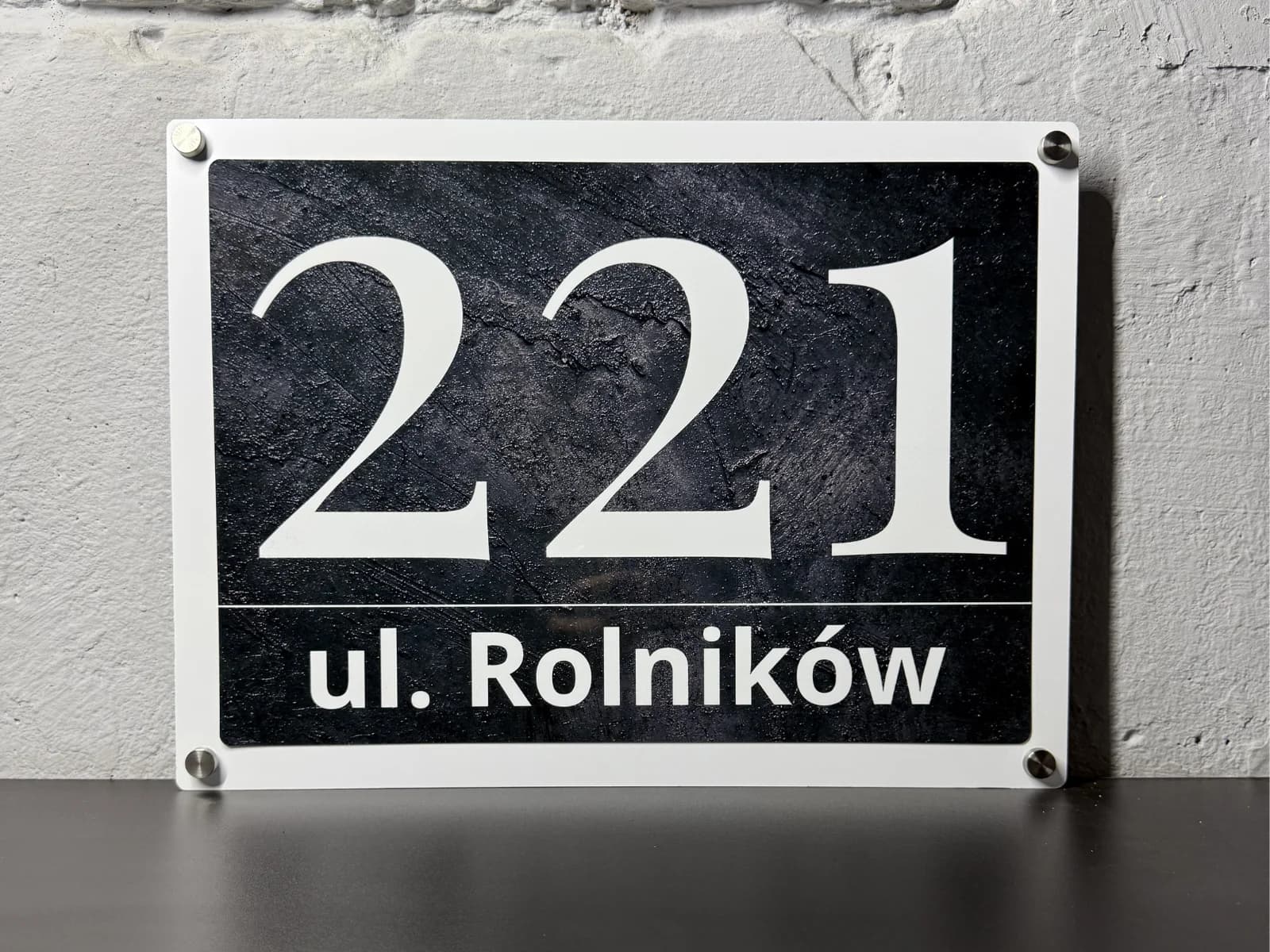 Zbliżenie na śruby dystansowe tabliczki adresowej Bolot Studio w klasycznym antracycie — detal mocowania