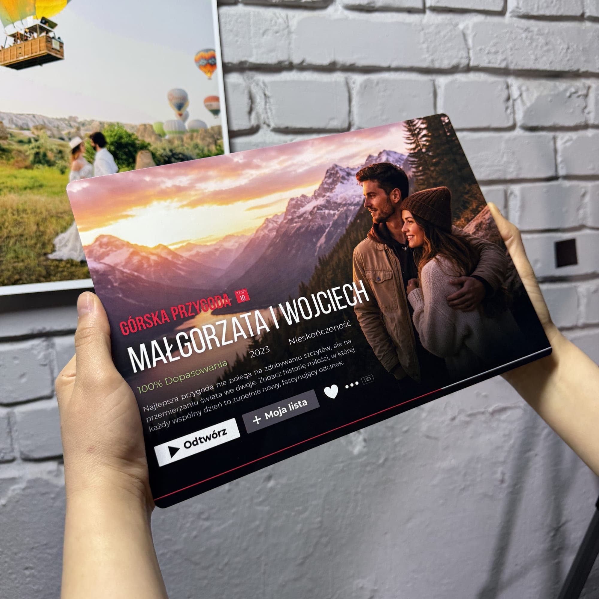 Hand holding a landscape Cinematic Print in front of a white brick wall